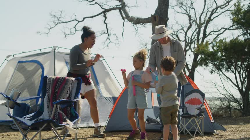 Family play with bubbles at campsite with water in the background