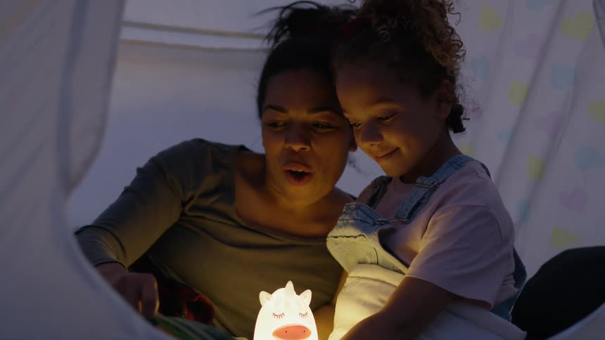 A mother and child are talking in a tent with an animal light
