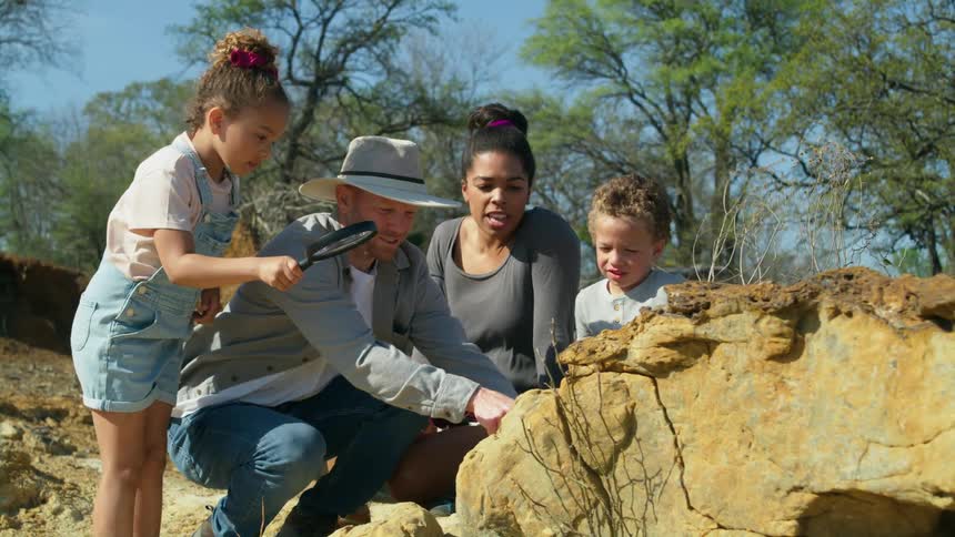 Family of four looking at the formations on a rock with a magnifying lens