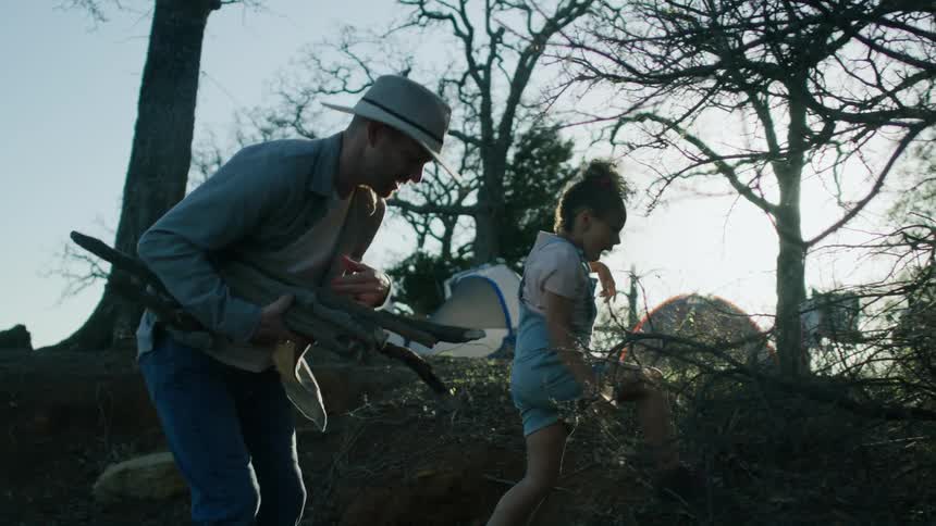 A father and daughter collect sticks for a fire