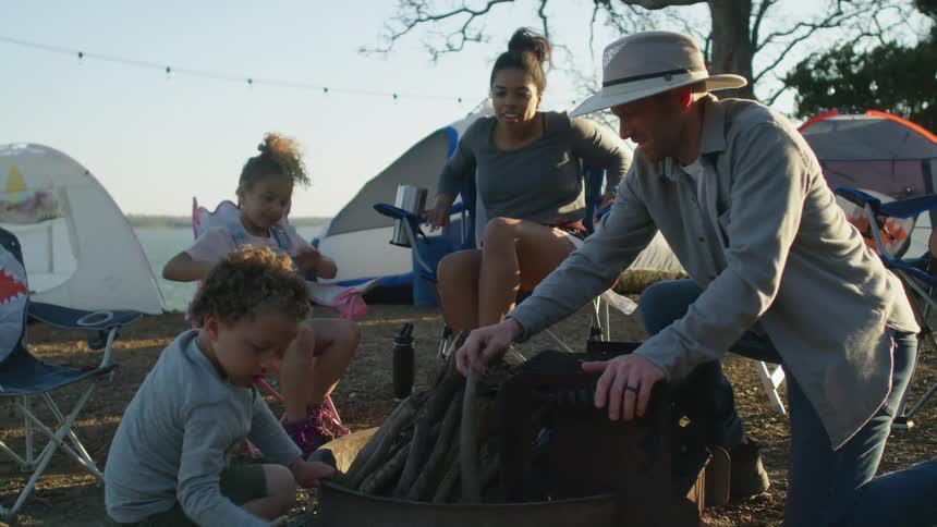 Family of four setting up on a camp near the coast at morning