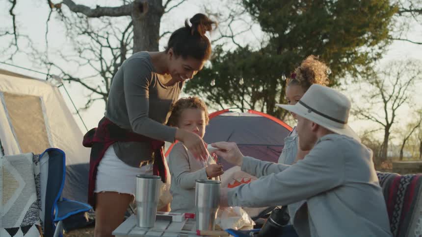 A man camping with his family puts a marshmallow on a stick for his son