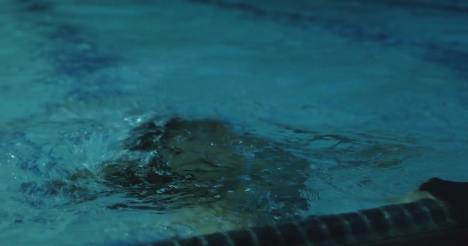 A woman is swimming in a pool at night