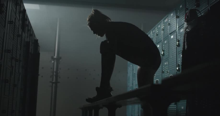 A woman puts on a shoe in a locker room