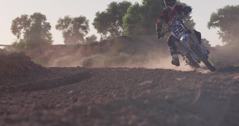 A man rides a dirt bike and churns up dust and dirt