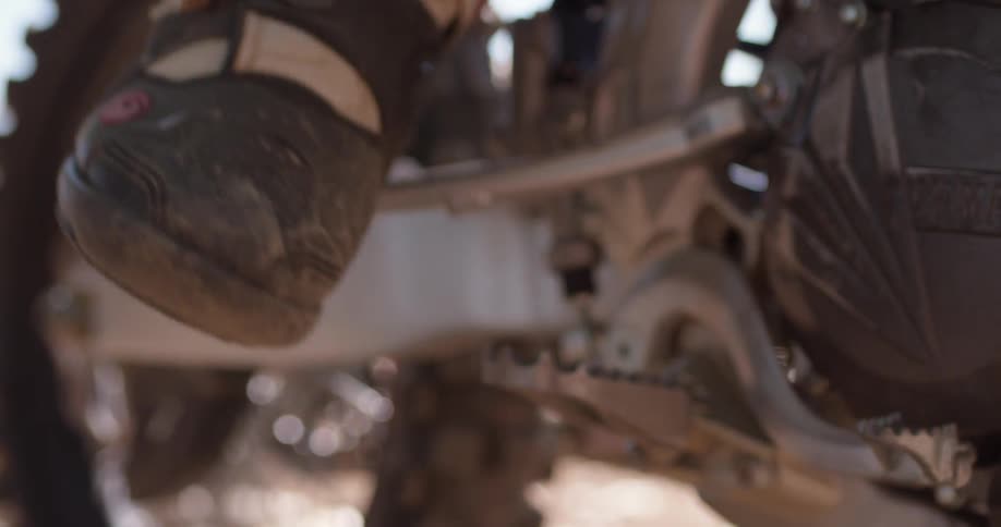A foot slams down the kick-starter on a motorcycle
