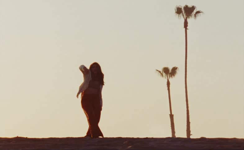 A woman is standing outdoors and dancing at dusk