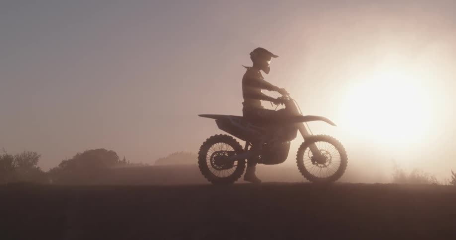 A person is sitting on their dirt bike on a cloudy day