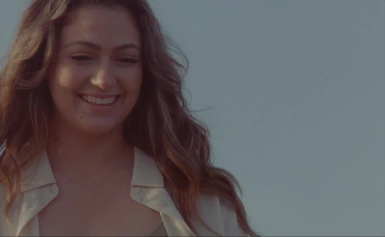 A woman laughs and smiles while posing outdoors