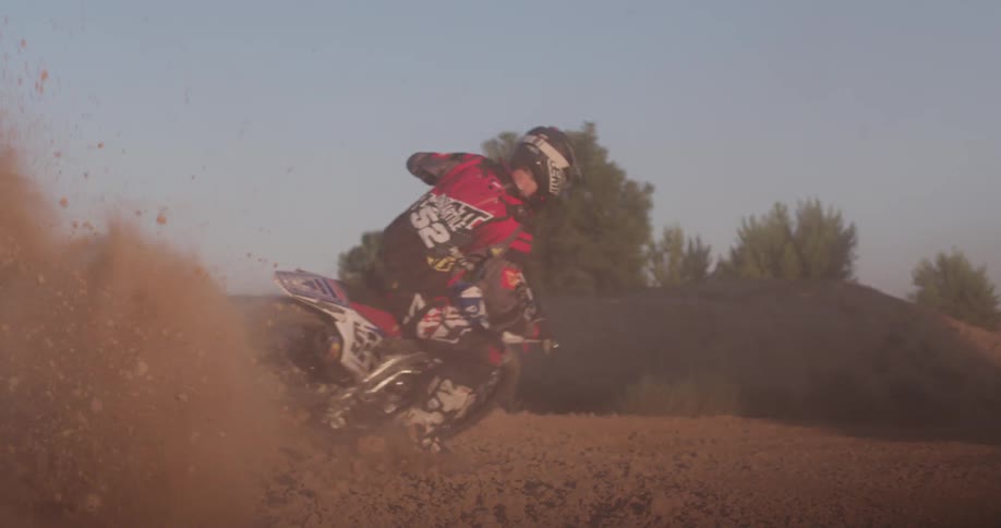 A dirt bike kicks up dust while making a sharp turn
