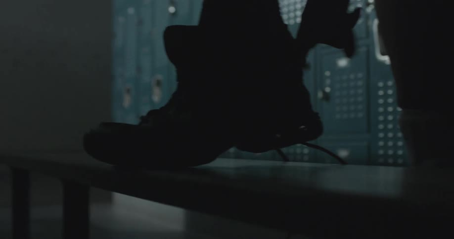 A person puts on their shoes in a locker room