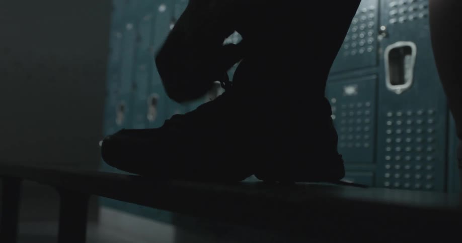 A person ties their shoes in a locker room