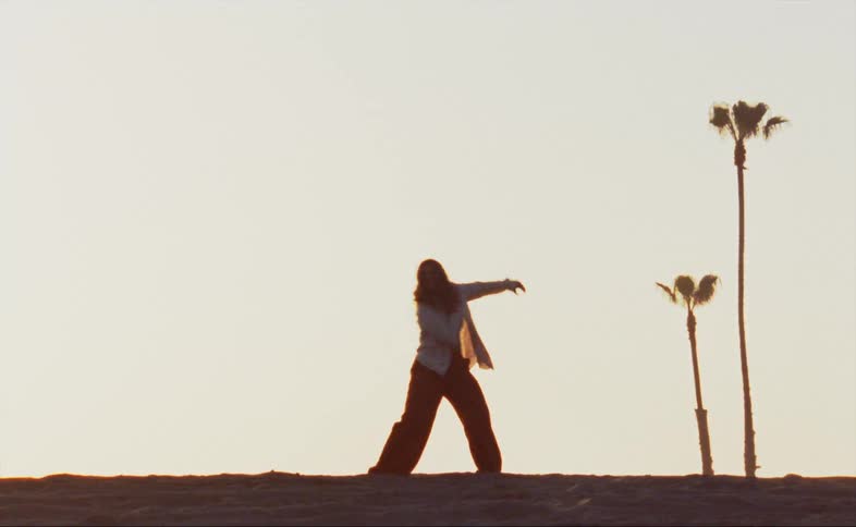 Female dances outdoors back lit by light outlining everything in red