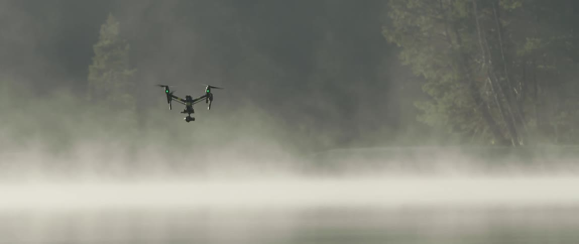 A drone is flying over a fog covered lake