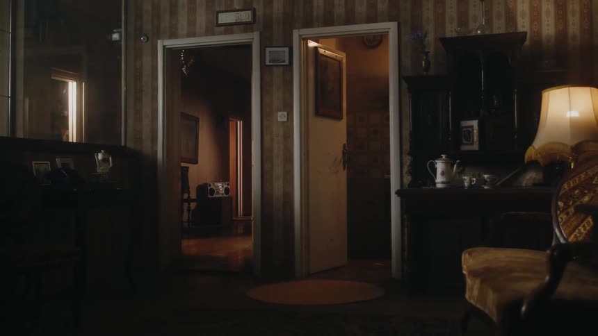 A dark room decorated with old fashioned items has wallpaper and antiques