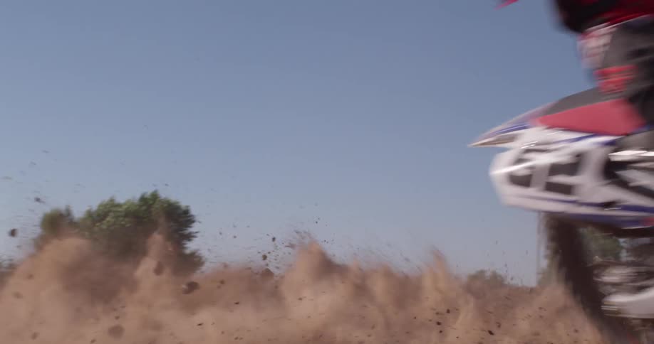 A person riding a dirt bike makes a sharp turn on the field