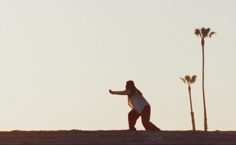 A woman does a modern dance barefoot in the grass