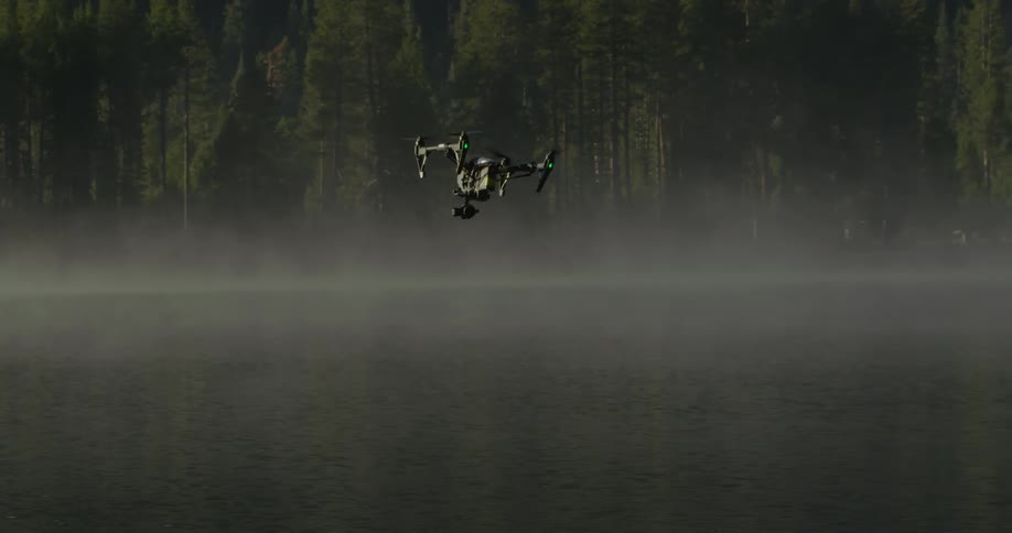 A drone is flying over a fog covered lake
