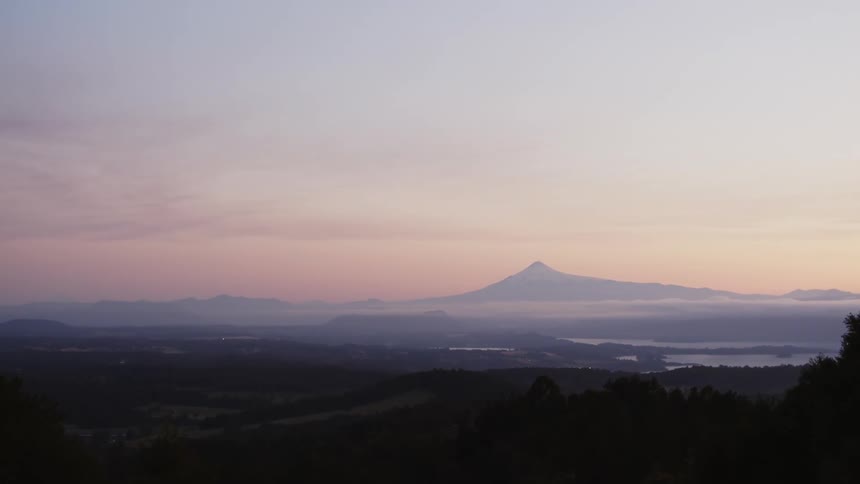 The sun sets over a mountain range and turns the sky pink in Chile