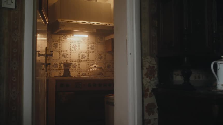 A moka pot sits on a stove in an old fashioned kitchen