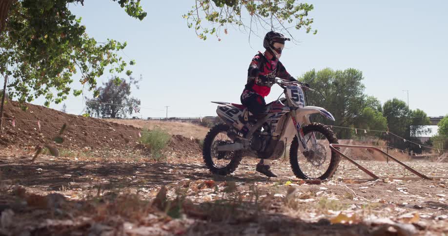 A man sits on and starts a dirt bike