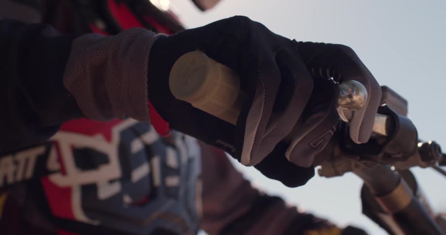 Close up of a dirt bike riders gloves on the handle
