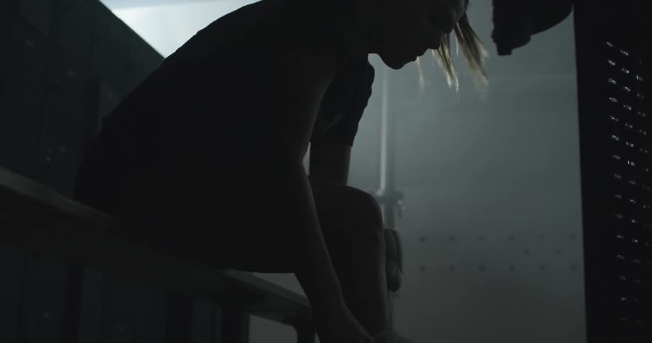 A woman puts on a knee pad in a locker room