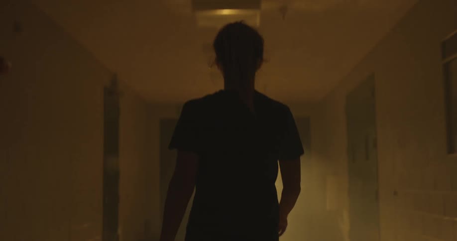 A woman is walking down a dark hall