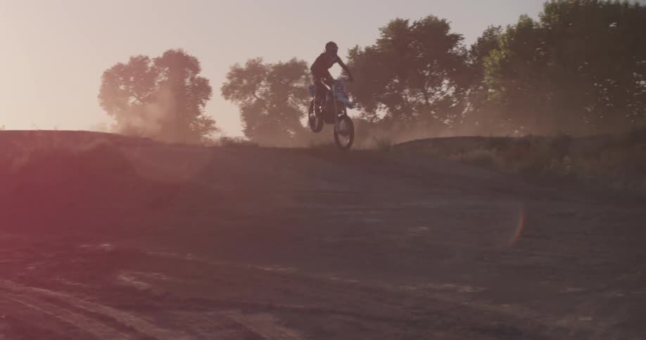 A person does a jump over a hill on a dirt bike