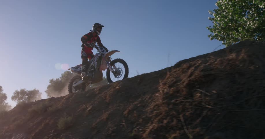 A person rides a dirt bike through a dusty field