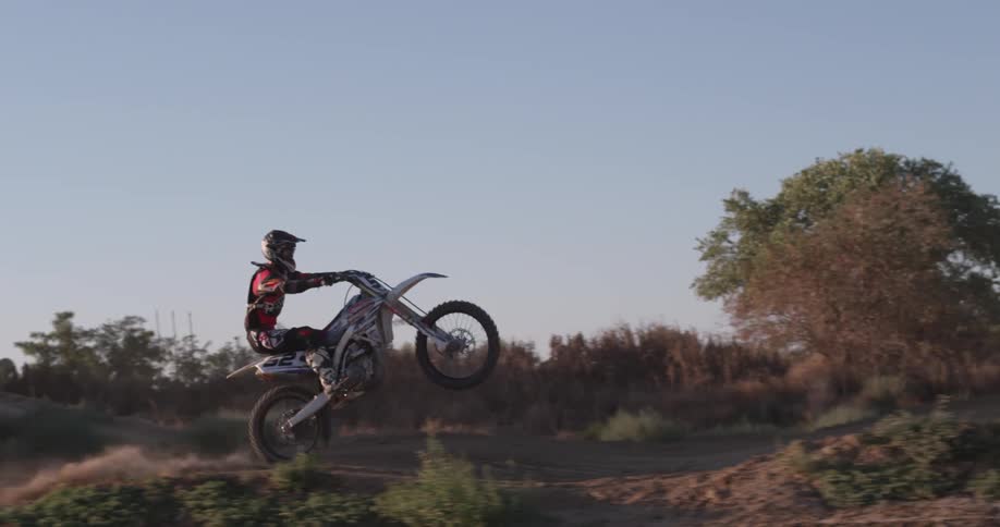 A man rides a dirt bike in a rural area