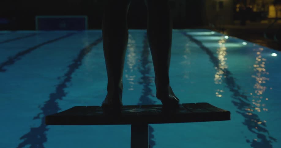 A woman dives into a pool from a platform