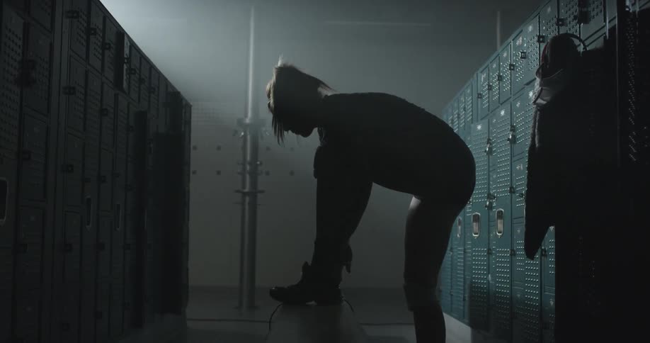 A woman puts on a shoe in a locker room