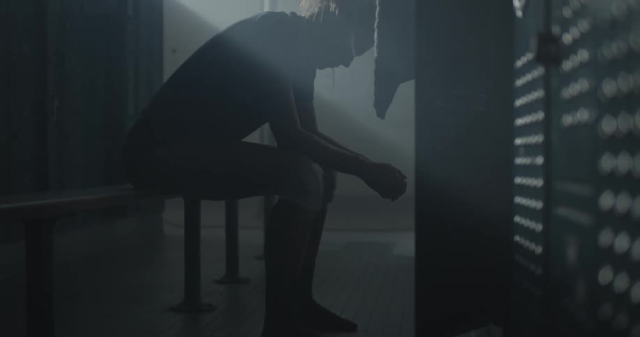 A woman is sitting in a dark gym