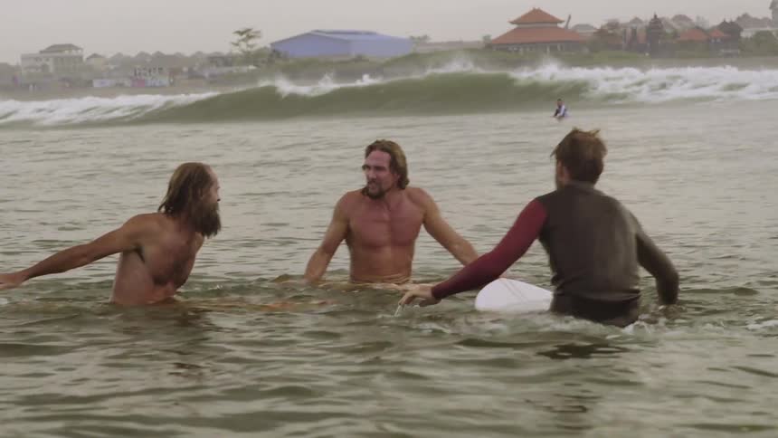 Three men are in the water splashing around