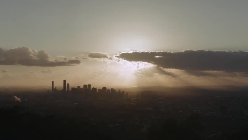 The sun shines through clouds over a cityscape