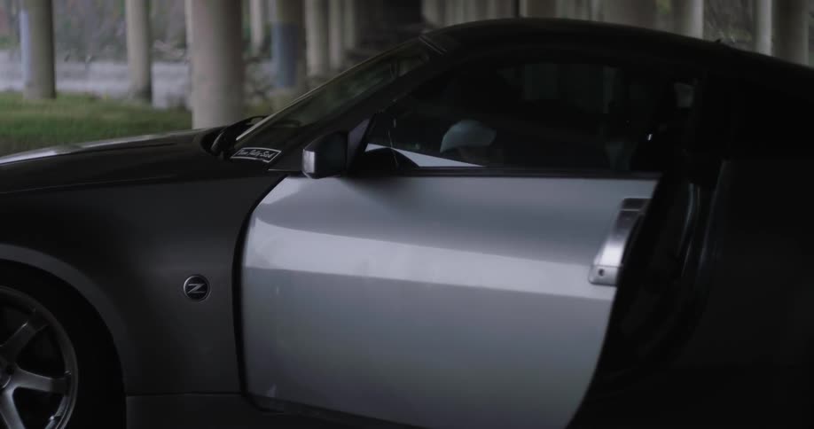 A man climbs out of a gray car