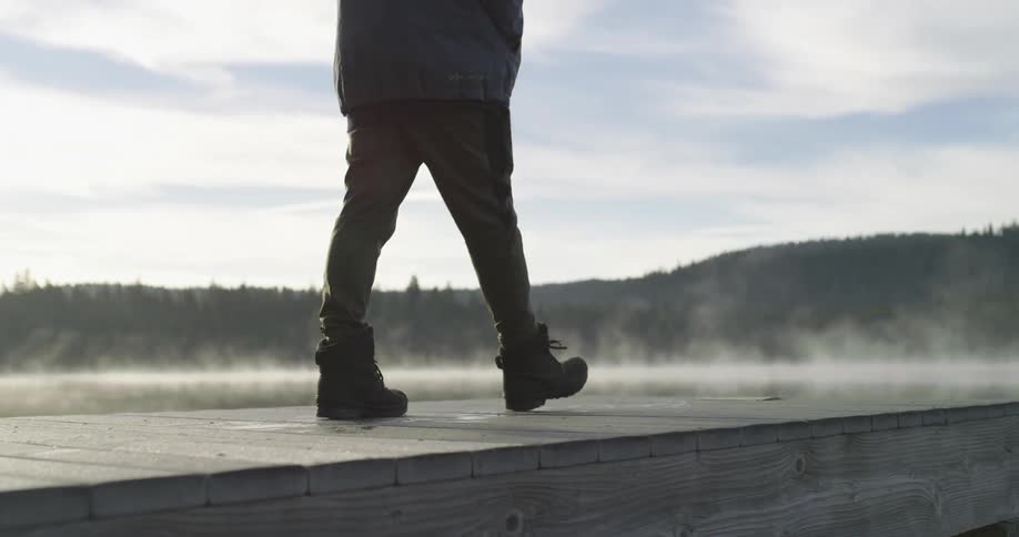 A man walks to the edge of a pier on a cloudy day