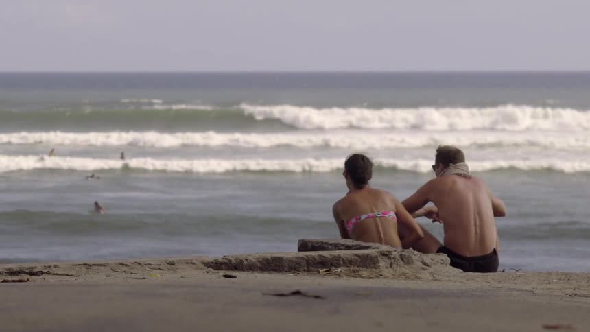 A man and a woman sit on the beach