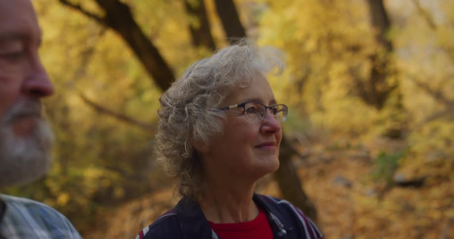 A woman smiles while walking through the woods with her husband