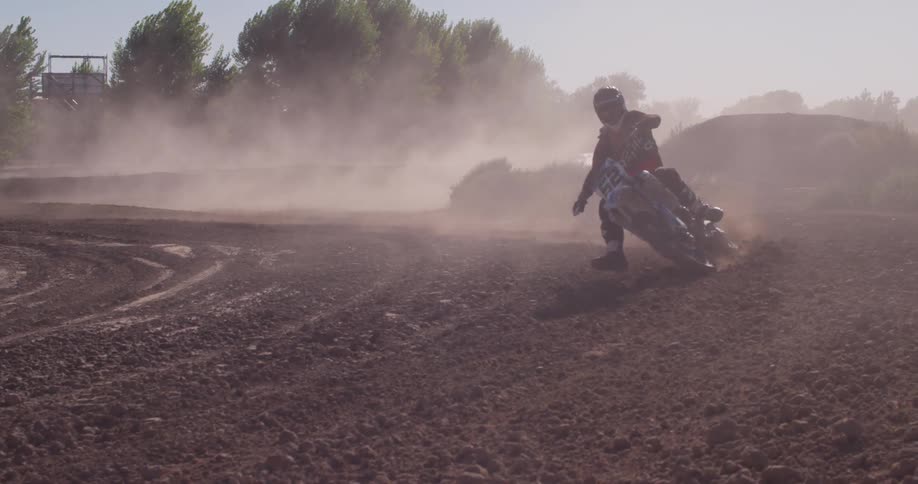 A bmx rider is doing sharp turns in the dirt