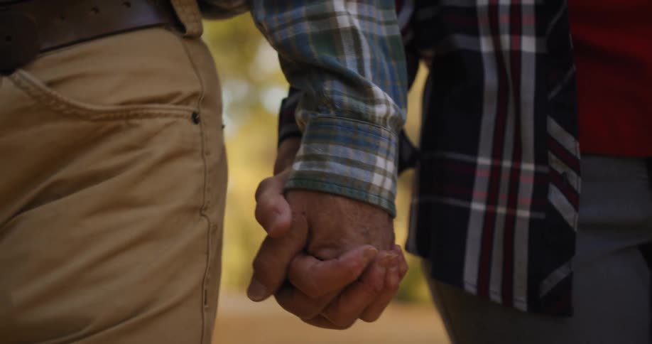 Older couple holds hands while walking along country road