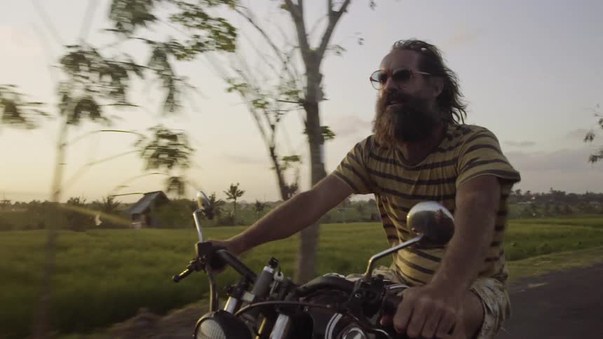 A man is riding a motorcycle without a helmet