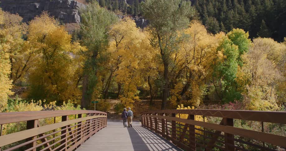 A man and woman walking across a bridge
