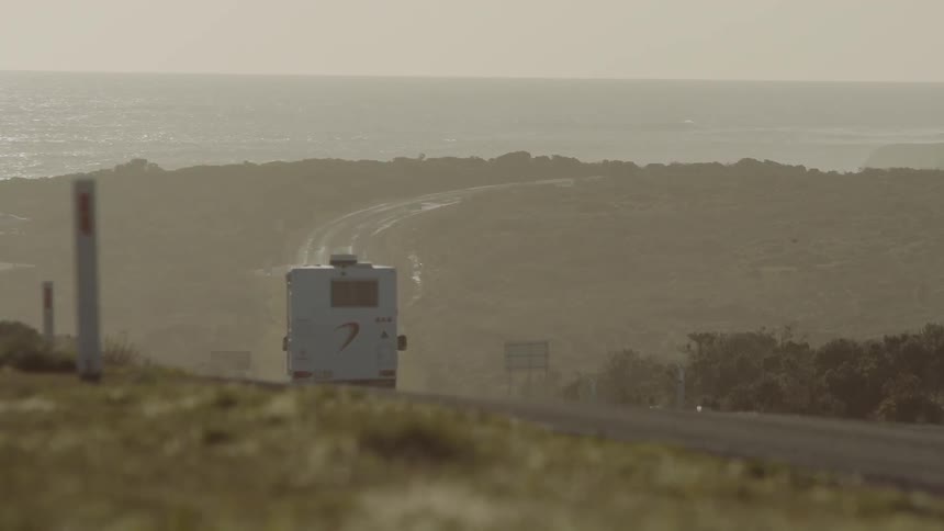 A caravan drives down a long stretch of road