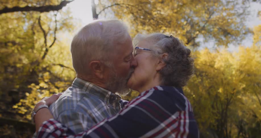 A couple hug and kiss while in the woods