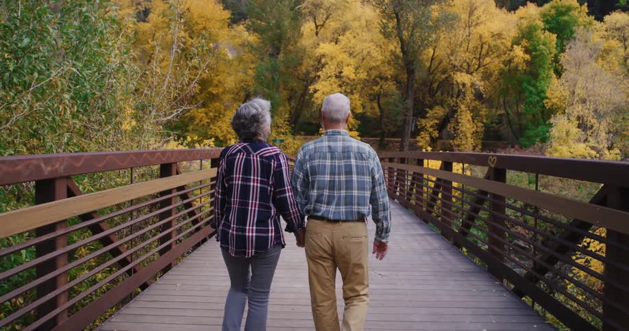 A couple hold hands as they walk over the bridge
