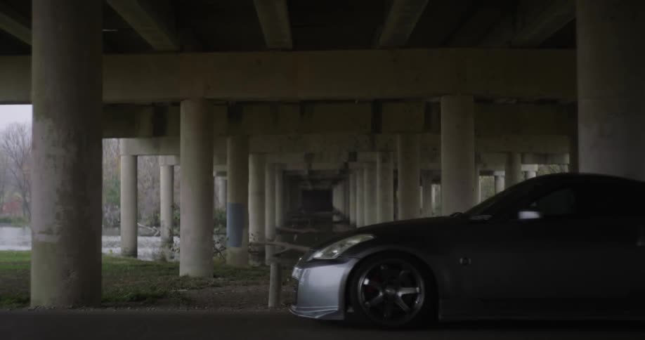 A sports car pulls up and stops under a bridge