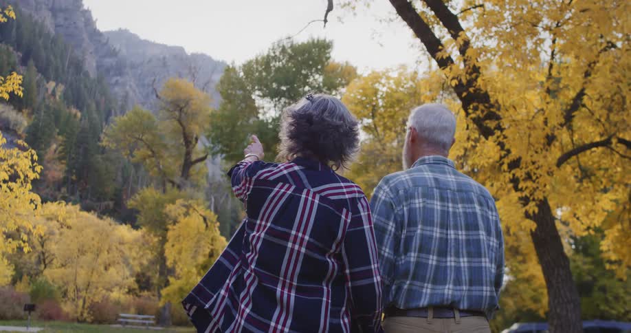 A woman points to the mountains ahead of her and a man as they walk