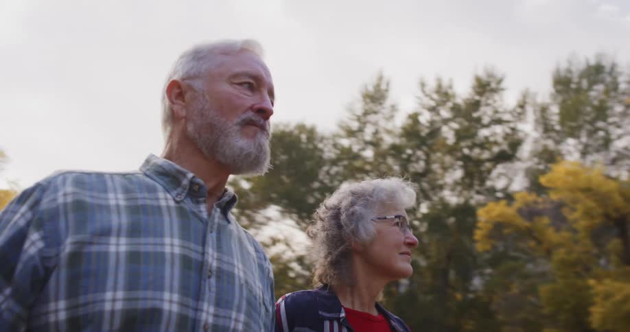 Elderly couple leisurely walking through the trees on a natural park in the mountains